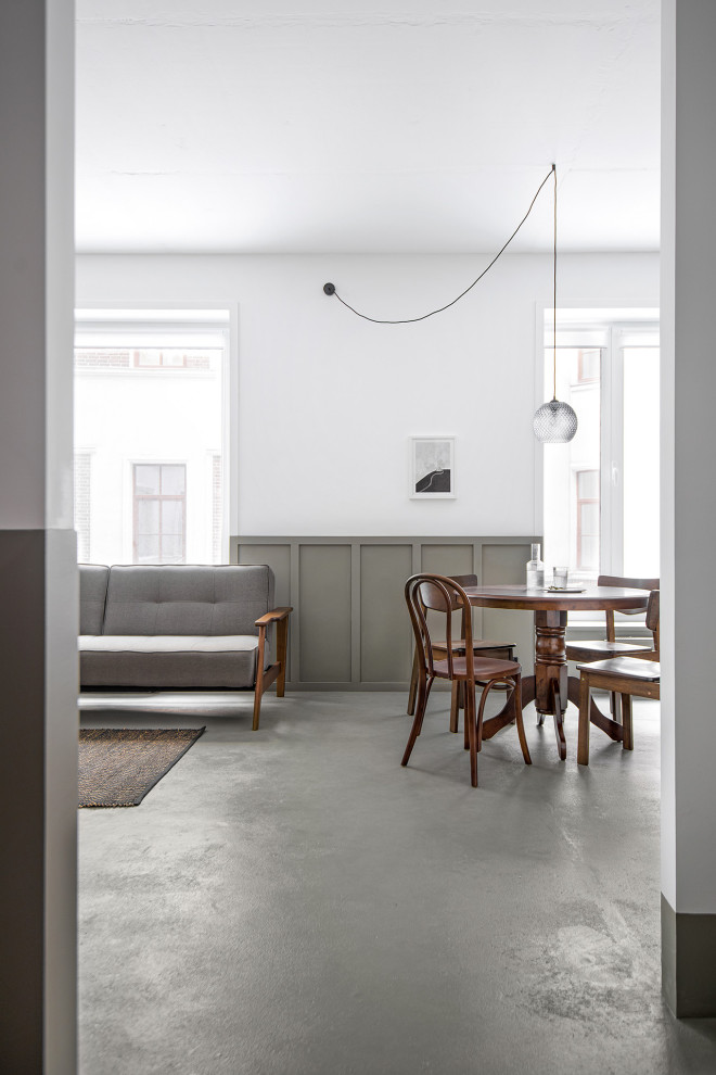 Imagen de comedor pequeño abierto con paredes blancas, suelo de cemento y suelo gris