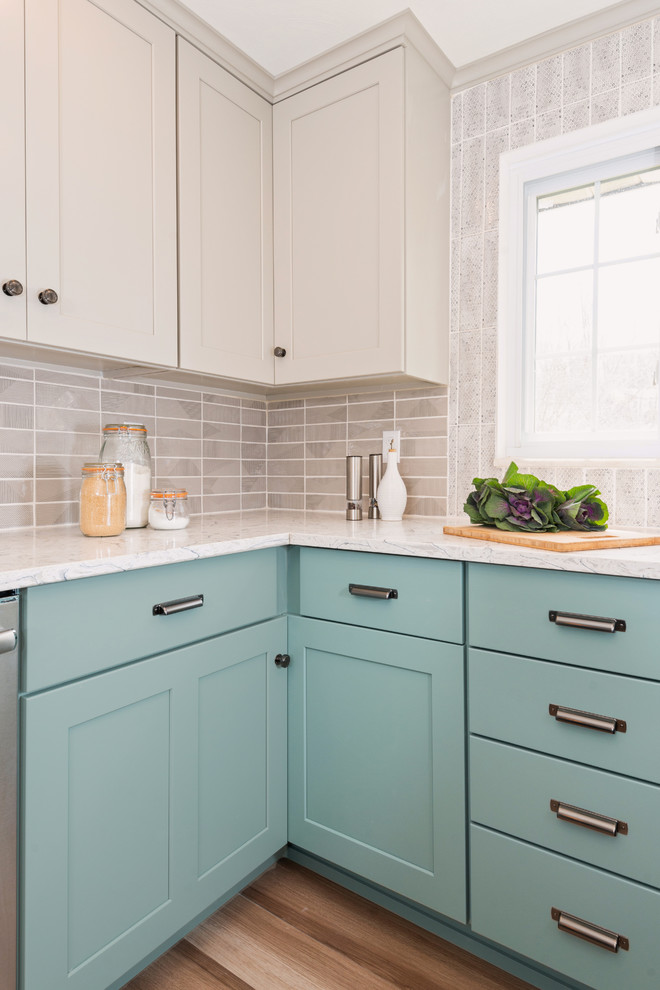 Example of a transitional u-shaped medium tone wood floor and brown floor enclosed kitchen design with an undermount sink, shaker cabinets, turquoise cabinets, quartzite countertops, gray backsplash, porcelain backsplash, stainless steel appliances, a peninsula and white countertops