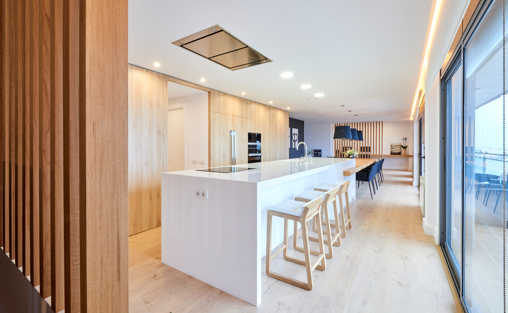 Photo of a large contemporary eat-in kitchen in Barcelona with an integrated sink, flat-panel cabinets, medium wood cabinets, quartz benchtops, black appliances, medium hardwood floors, with island and beige floor.
