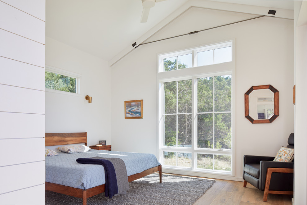 Photo of a scandinavian bedroom in Austin with white walls, medium hardwood floors and brown floor.