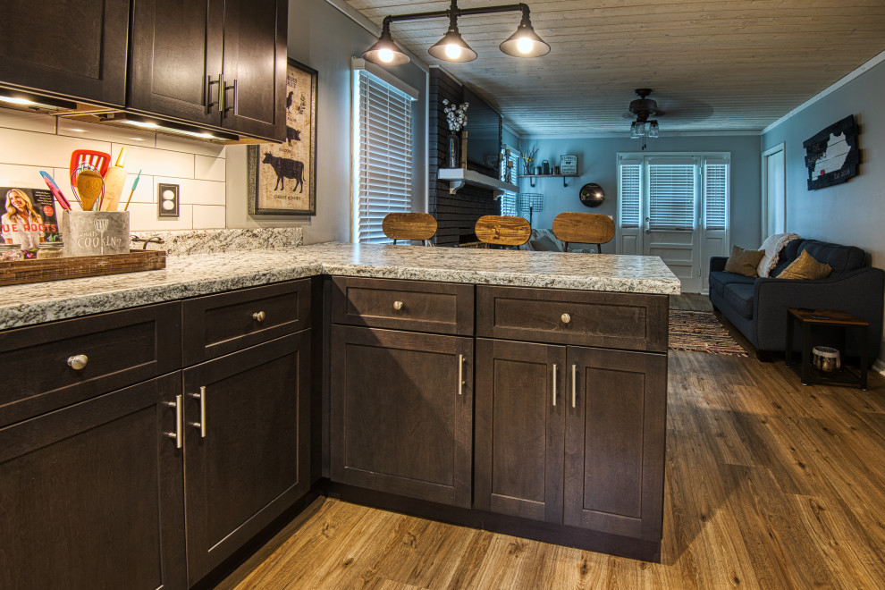 Example of a mid-sized transitional u-shaped light wood floor and brown floor open concept kitchen design with a drop-in sink, shaker cabinets, gray cabinets, laminate countertops, white backsplash, subway tile backsplash, stainless steel appliances, a peninsula and white countertops
