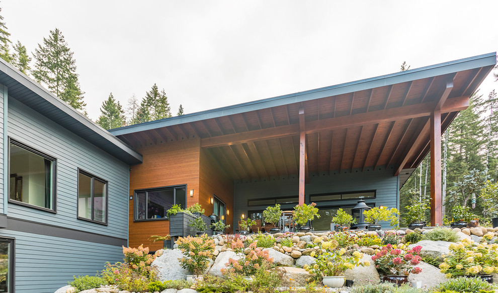 Photo of an expansive modern two-storey blue house exterior in Vancouver with concrete fiberboard siding, a shed roof and a metal roof.
