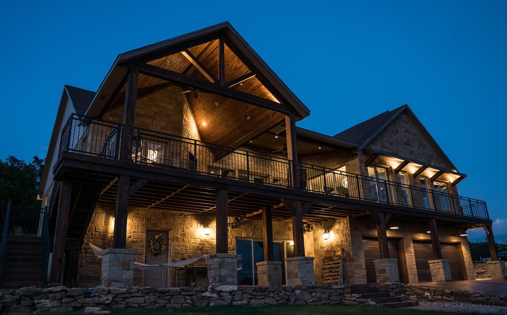 Example of a large mountain style backyard deck design in Austin with a roof extension