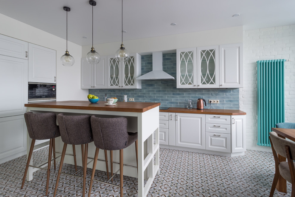 This is an example of a mid-sized traditional l-shaped eat-in kitchen in Saint Petersburg with white cabinets, wood benchtops, ceramic splashback, ceramic floors, with island, raised-panel cabinets, blue splashback, multi-coloured floor, brown benchtop and stainless steel appliances.