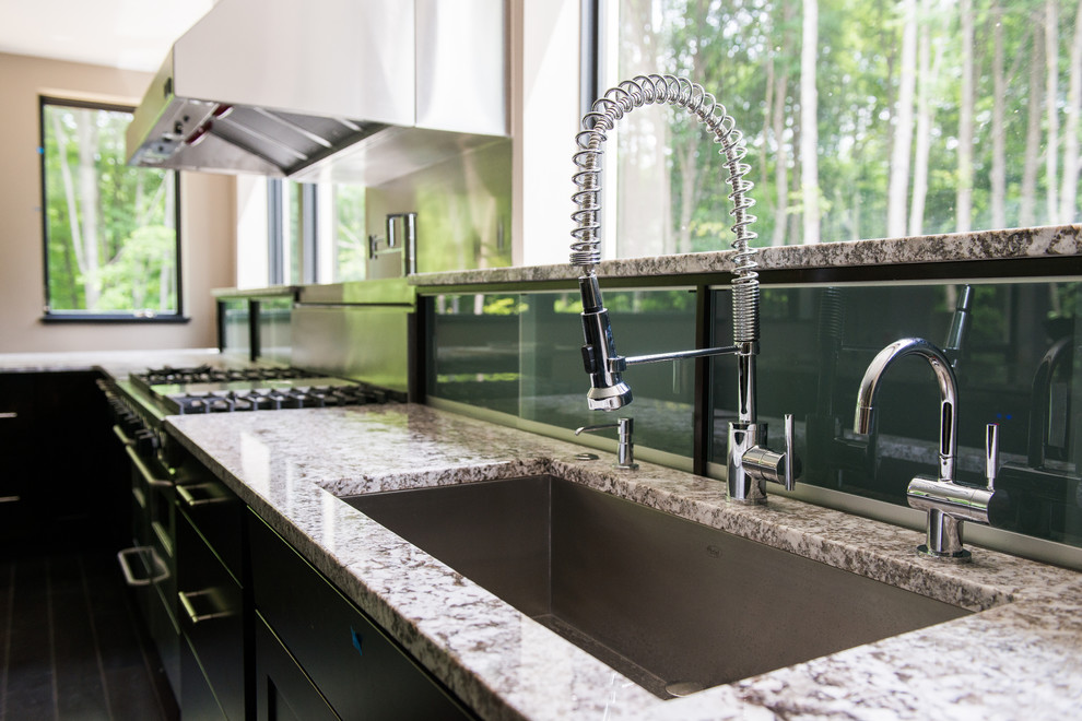 Example of a large trendy l-shaped dark wood floor kitchen design in Cleveland with an undermount sink, recessed-panel cabinets, dark wood cabinets, glass sheet backsplash, stainless steel appliances and an island