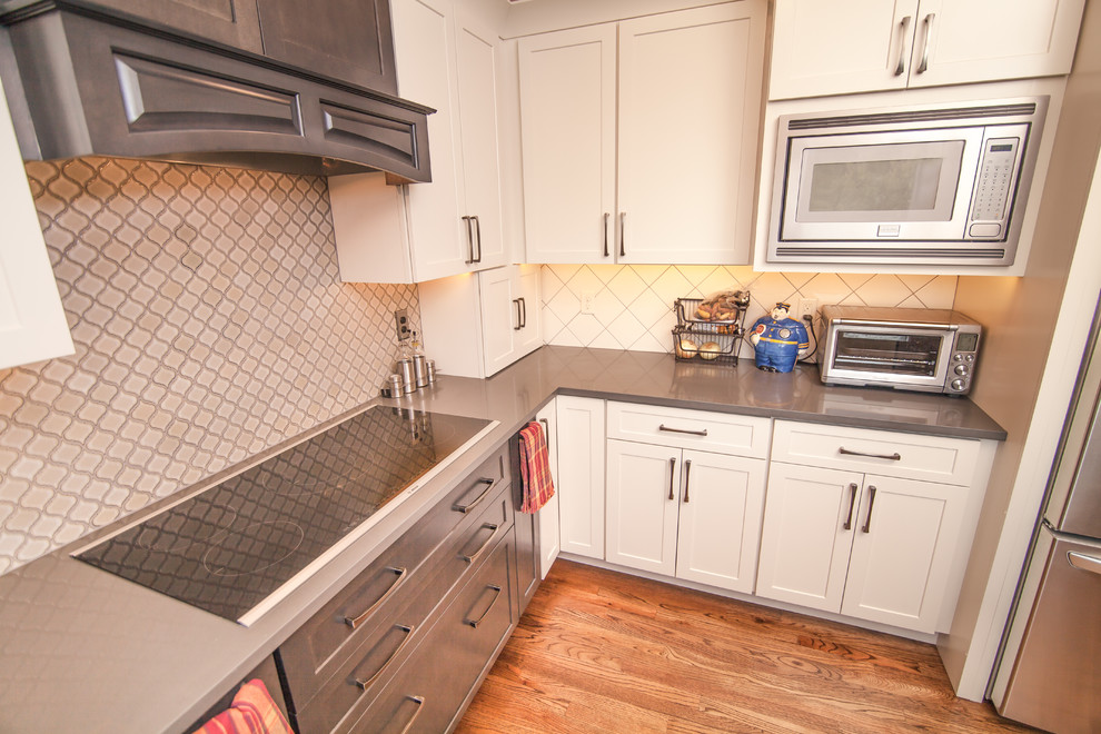 Inspiration for a mid-sized transitional u-shaped light wood floor eat-in kitchen remodel in Boise with a double-bowl sink, shaker cabinets, white cabinets, quartz countertops, white backsplash, ceramic backsplash, stainless steel appliances and an island