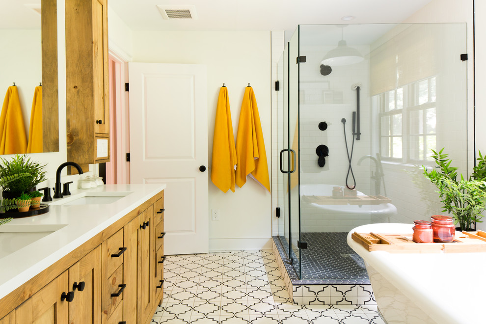 Design ideas for a large transitional master bathroom in Raleigh with shaker cabinets, medium wood cabinets, a claw-foot tub, an open shower, a two-piece toilet, white tile, white walls, cement tiles, an undermount sink, limestone benchtops, white floor, a hinged shower door and white benchtops.