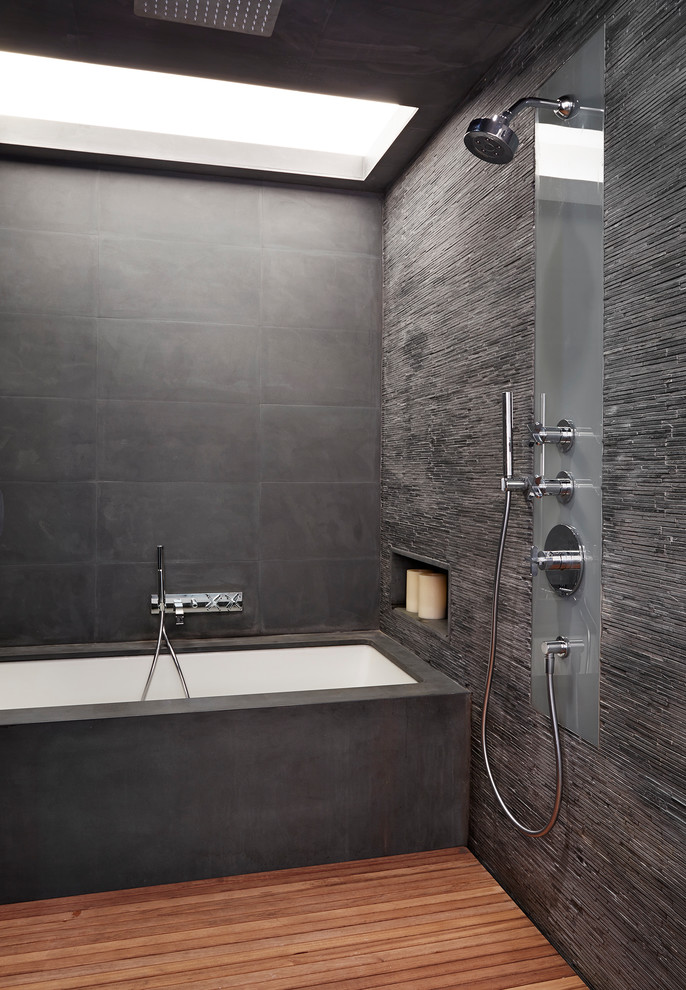 This is an example of an expansive contemporary master bathroom in New York with an alcove tub, an open shower, gray tile, matchstick tile, grey walls, medium hardwood floors and an open shower.