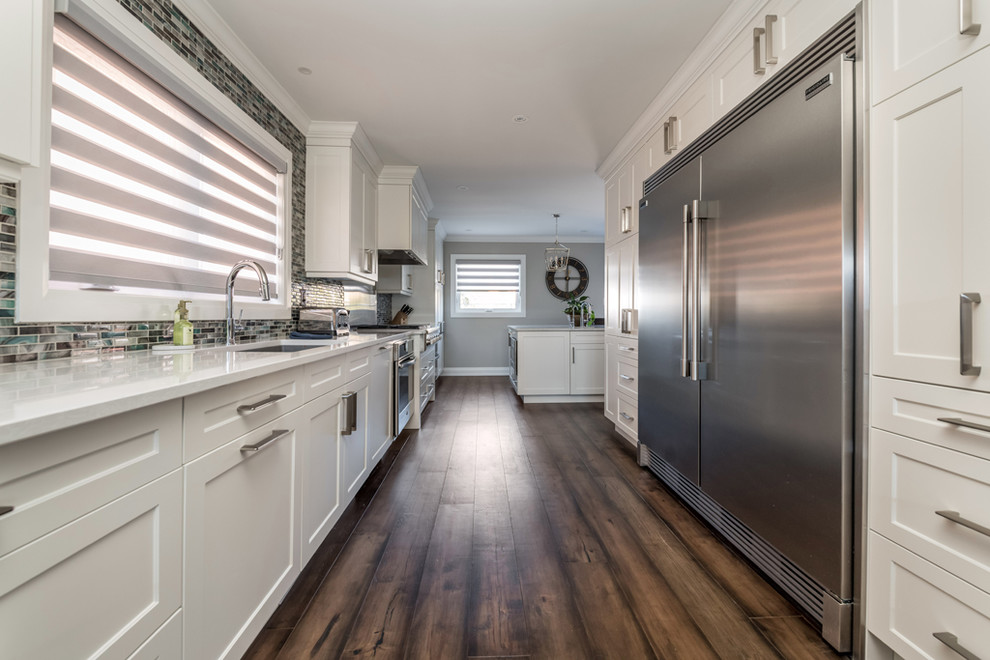 Eat-in kitchen - large transitional galley dark wood floor and brown floor eat-in kitchen idea with an undermount sink, shaker cabinets, white cabinets, quartz countertops, multicolored backsplash, mosaic tile backsplash, stainless steel appliances, an island and multicolored countertops