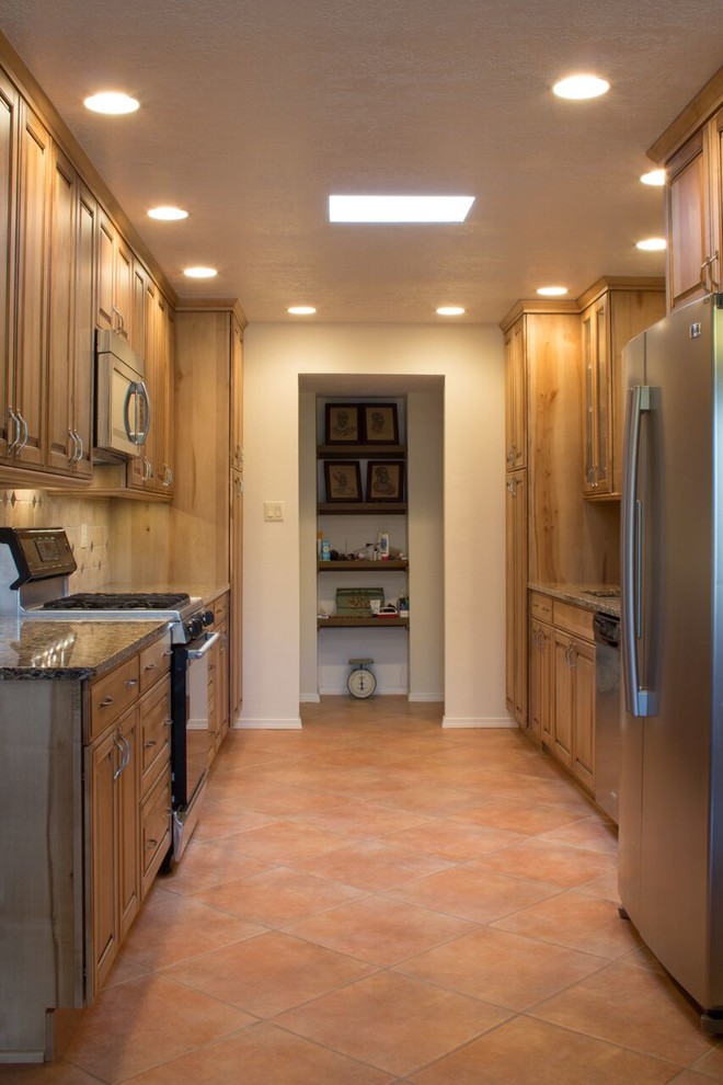Inspiration for a mid-sized traditional galley separate kitchen in Orange County with an undermount sink, raised-panel cabinets, light wood cabinets, granite benchtops, beige splashback, ceramic splashback, stainless steel appliances and ceramic floors.