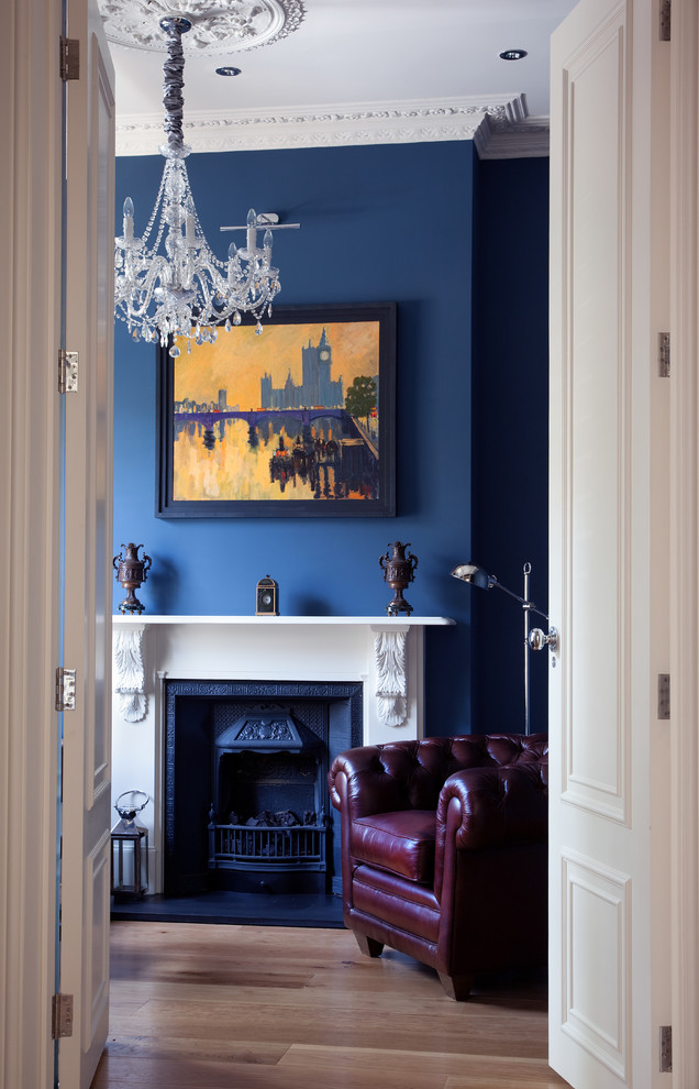 This is an example of a traditional home office in London with blue walls, medium hardwood floors and a standard fireplace.
