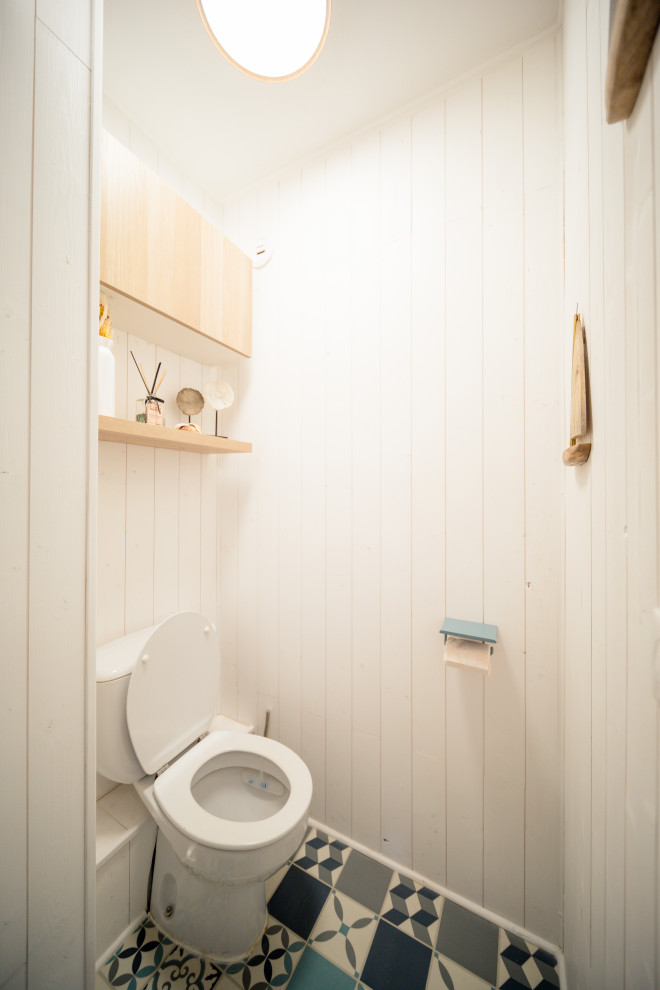 Design ideas for a small beach style powder room in Nice with light wood cabinets, a one-piece toilet, white tile, white walls, vinyl floors, blue floor, white benchtops, a floating vanity and planked wall panelling.