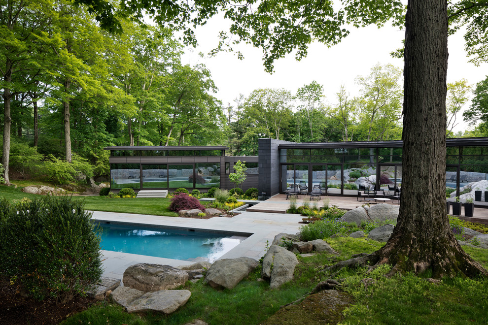 Mid-sized contemporary one-storey glass grey house exterior in New York with a flat roof.