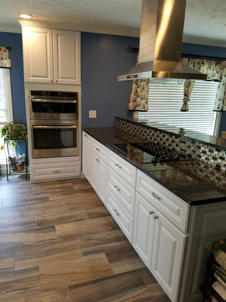 Example of a mid-sized transitional galley medium tone wood floor and beige floor eat-in kitchen design in Atlanta with an undermount sink, raised-panel cabinets, white cabinets, quartz countertops, beige backsplash, subway tile backsplash, stainless steel appliances and a peninsula
