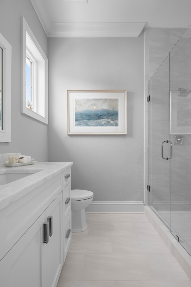 Inspiration for a mid-sized beach style master bathroom in Orlando with shaker cabinets, white cabinets, an alcove shower, white tile, marble, grey walls, porcelain floors, an undermount sink, engineered quartz benchtops, white floor and a hinged shower door.