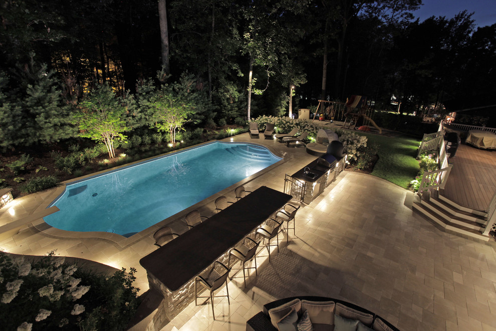 Inspiration for an expansive transitional backyard custom-shaped pool in New York with tile.
