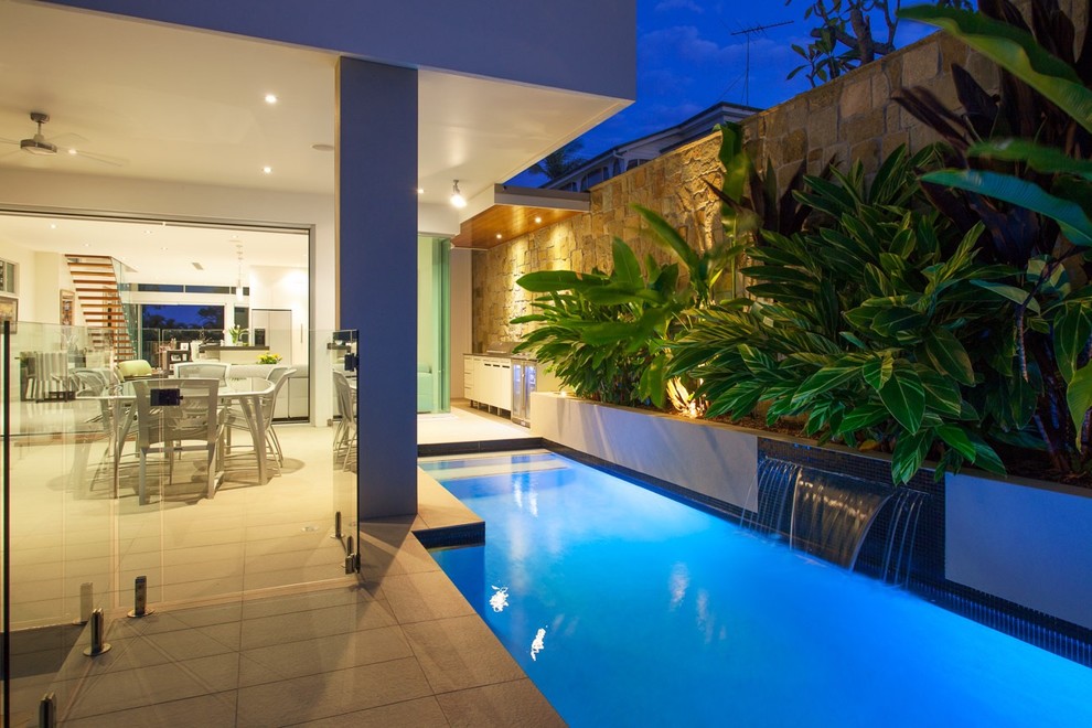 This is an example of a small modern backyard rectangular lap pool in Brisbane with tile.