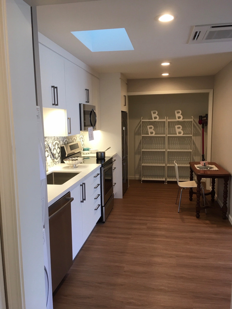 Small transitional single-wall kitchen pantry in San Francisco with a single-bowl sink, flat-panel cabinets, white cabinets, quartz benchtops, grey splashback, porcelain splashback, stainless steel appliances, vinyl floors, no island, brown floor and white benchtop.