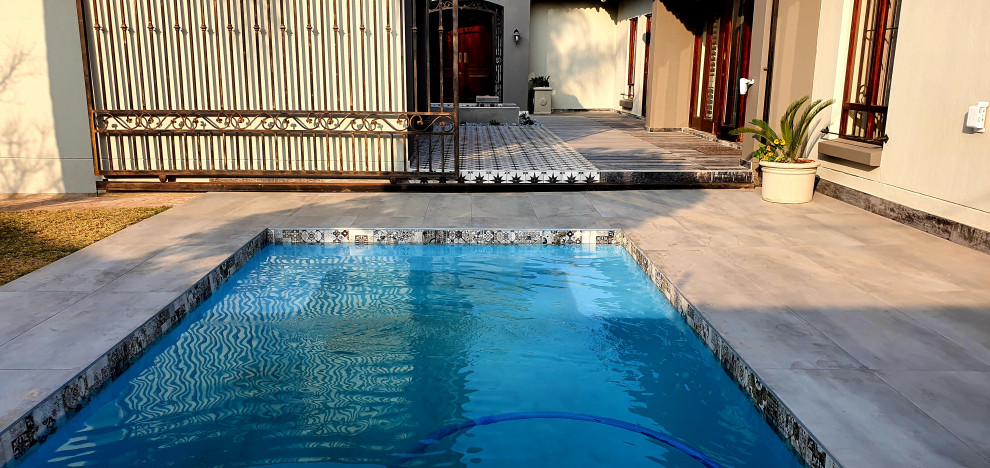 Ejemplo de piscina con fuente mediterránea de tamaño medio rectangular en patio con suelo de baldosas