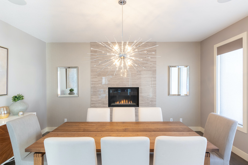 This is an example of a mid-sized modern separate dining room in Calgary with grey walls, dark hardwood floors, a standard fireplace, a tile fireplace surround, brown floor and wallpaper.