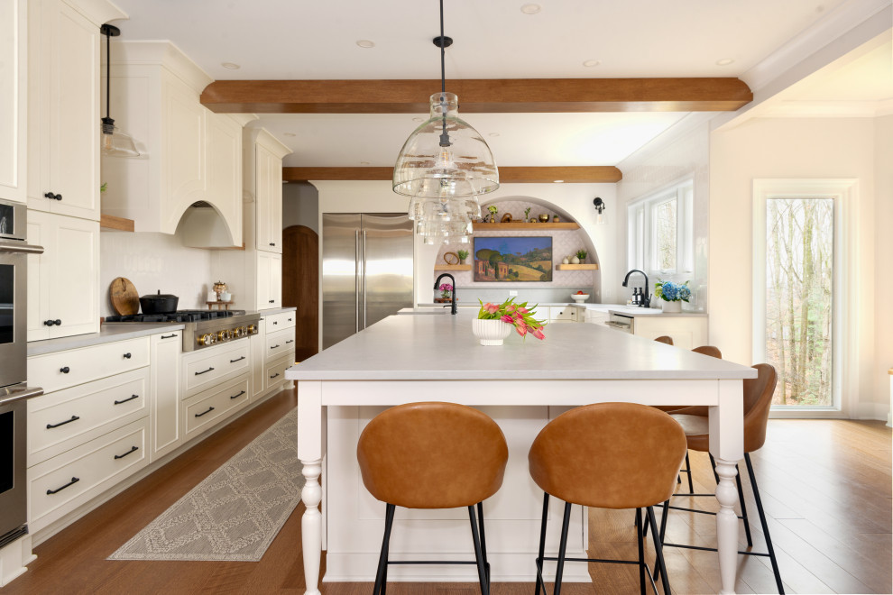 Eat-in kitchen - large medium tone wood floor and exposed beam eat-in kitchen idea with white backsplash, stainless steel appliances and an island