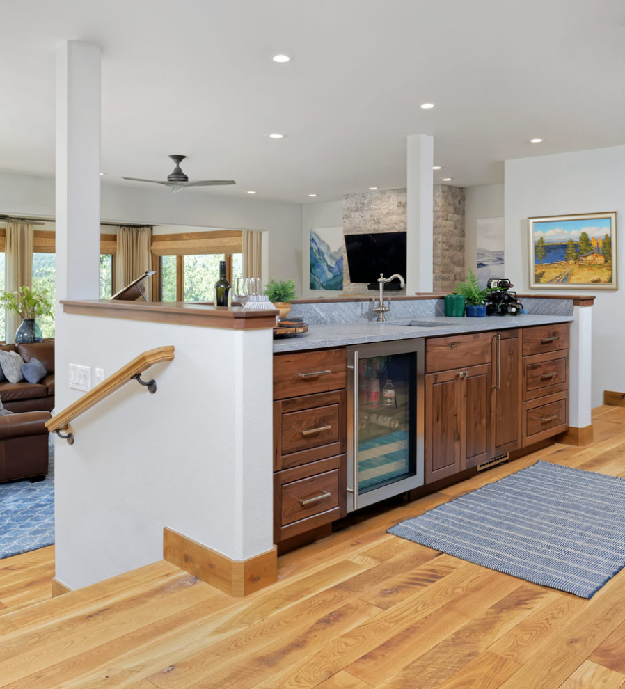 Mid-sized mountain style l-shaped medium tone wood floor open concept kitchen photo with an undermount sink, shaker cabinets, granite countertops, beige backsplash, stainless steel appliances and an island