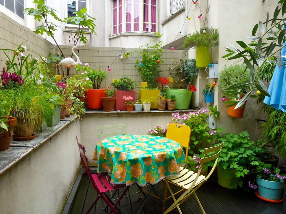 This is an example of a small eclectic deck in Paris with a container garden and no cover.