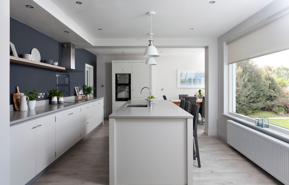 This is an example of a transitional kitchen in Dublin with flat-panel cabinets, white cabinets and with island.