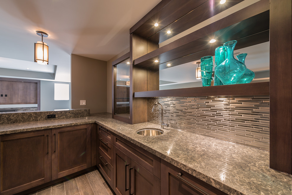 This is an example of a large contemporary u-shaped wet bar in Other with an undermount sink, shaker cabinets, dark wood cabinets, granite benchtops, grey splashback, matchstick tile splashback and medium hardwood floors.