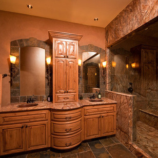 Sauna - large rustic multicolored tile and stone tile slate floor sauna idea with an undermount sink, raised-panel cabinets, medium tone wood cabinets, marble countertops, a two-piece toilet and brown walls