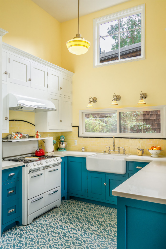 This is an example of a small country u-shaped eat-in kitchen in Los Angeles with a farmhouse sink, beaded inset cabinets, blue cabinets, quartz benchtops, yellow splashback, subway tile splashback, white appliances, cement tiles, blue floor and white benchtop.