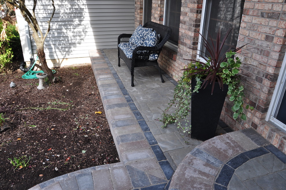 Inspiration for a mid-sized traditional front yard verandah in Chicago with brick pavers and a roof extension.