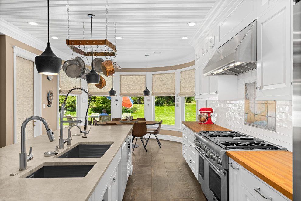 Design ideas for an expansive contemporary galley eat-in kitchen in Seattle with an undermount sink, shaker cabinets, white cabinets, quartz benchtops, white splashback, subway tile splashback, stainless steel appliances, porcelain floors, with island, brown floor, beige benchtop and timber.