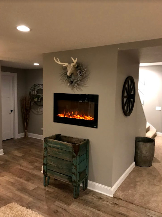Example of a large transitional underground light wood floor and beige floor basement design with beige walls, a standard fireplace and a metal fireplace