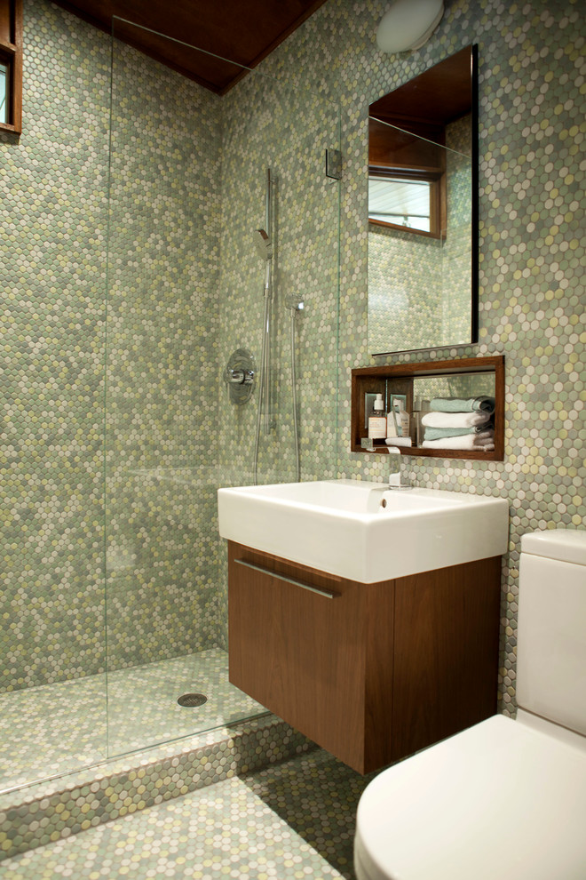 This is an example of a small midcentury 3/4 bathroom in New York with an integrated sink, flat-panel cabinets, medium wood cabinets, an alcove shower, a two-piece toilet, green tile, mosaic tile, green walls, mosaic tile floors and green floor.
