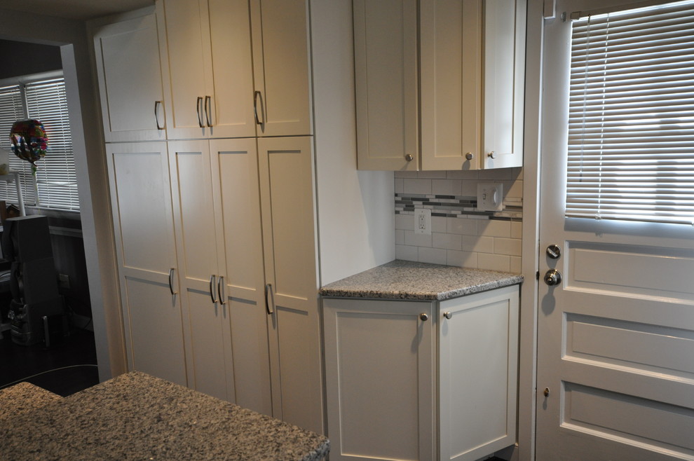 Mid-sized transitional l-shaped dark wood floor and brown floor open concept kitchen photo in DC Metro with an undermount sink, shaker cabinets, white cabinets, white backsplash, subway tile backsplash, stainless steel appliances and an island