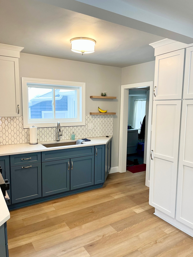 Example of a mid-sized transitional u-shaped vinyl floor and brown floor eat-in kitchen design with an undermount sink, shaker cabinets, white cabinets, quartz countertops, white backsplash, ceramic backsplash, stainless steel appliances, no island and white countertops