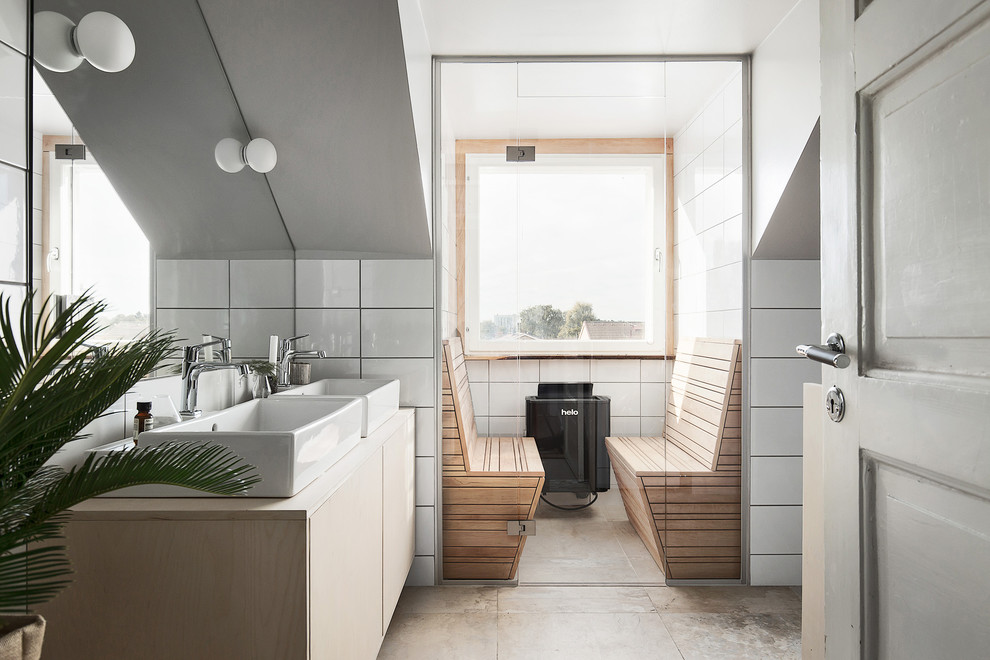 This is an example of a mid-sized scandinavian bathroom in Stockholm with flat-panel cabinets, light wood cabinets, a vessel sink, ceramic tile, white walls and wood benchtops.
