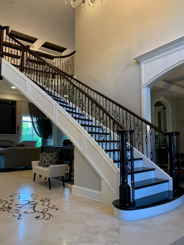 Photo of a large transitional wood curved staircase in Chicago with wood risers, metal railing and wood walls.
