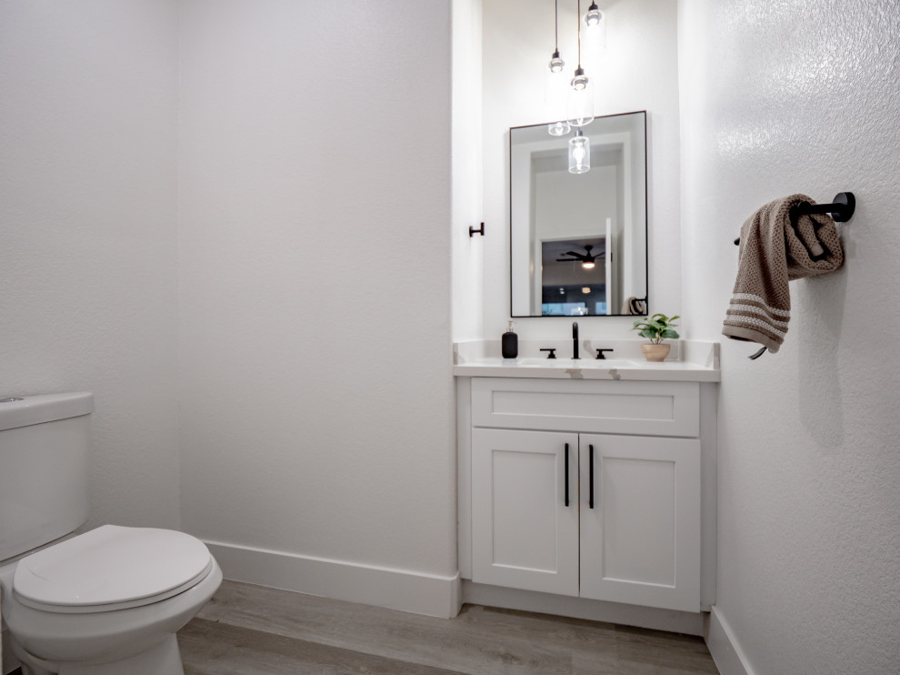 Small modern cloakroom in Las Vegas with shaker cabinets, white cabinets, a two-piece toilet, white walls, laminate floors, a submerged sink, quartz worktops, grey floors, white worktops and a built in vanity unit.