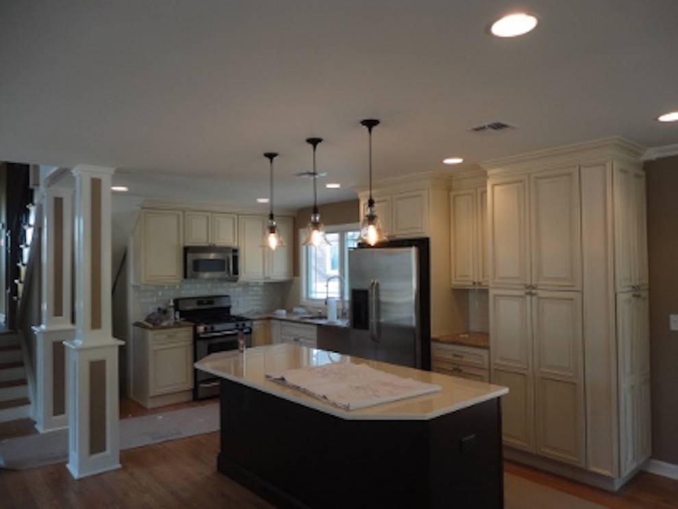 Kitchen - transitional l-shaped medium tone wood floor kitchen idea in New York with distressed cabinets, granite countertops, beige backsplash, ceramic backsplash, stainless steel appliances and an island