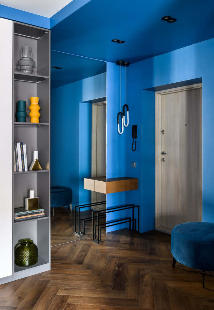Bild på en mellanstor funkis ingång och ytterdörr, med blå väggar, mellanmörkt trägolv, en enkeldörr, ljus trädörr och brunt golv