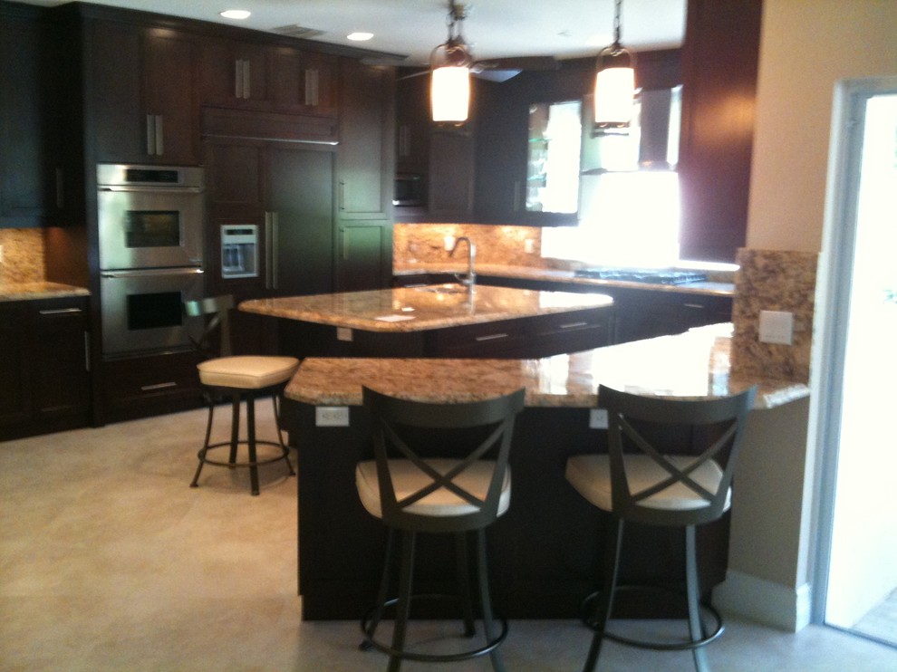 Example of a large transitional u-shaped travertine floor and beige floor open concept kitchen design in Miami with an undermount sink, shaker cabinets, dark wood cabinets, granite countertops, multicolored backsplash, stone tile backsplash, stainless steel appliances and an island
