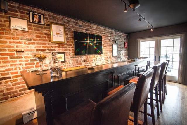 Inspiration for a large traditional single-wall seated home bar in Philadelphia with wood benchtops, red splashback, brick splashback, dark hardwood floors, brown floor and brown benchtop.