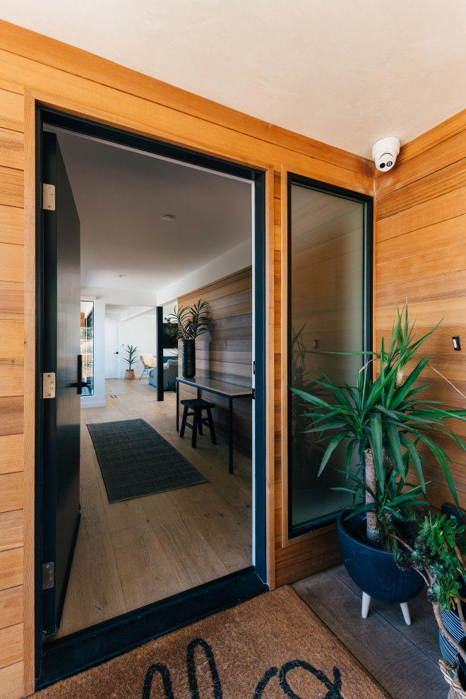Kleine Haustür mit hellem Holzboden, Einzeltür, schwarzer Haustür, grauem Boden und Holzwänden in Orange County