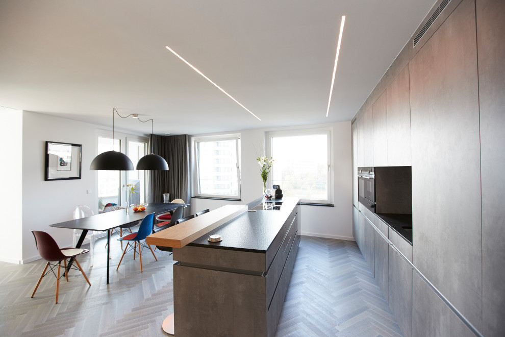 Kleine, Offene, Einzeilige Moderne Küche mit gebeiztem Holzboden, grauem Boden, Kassettenfronten, grauen Schränken und Kücheninsel in München