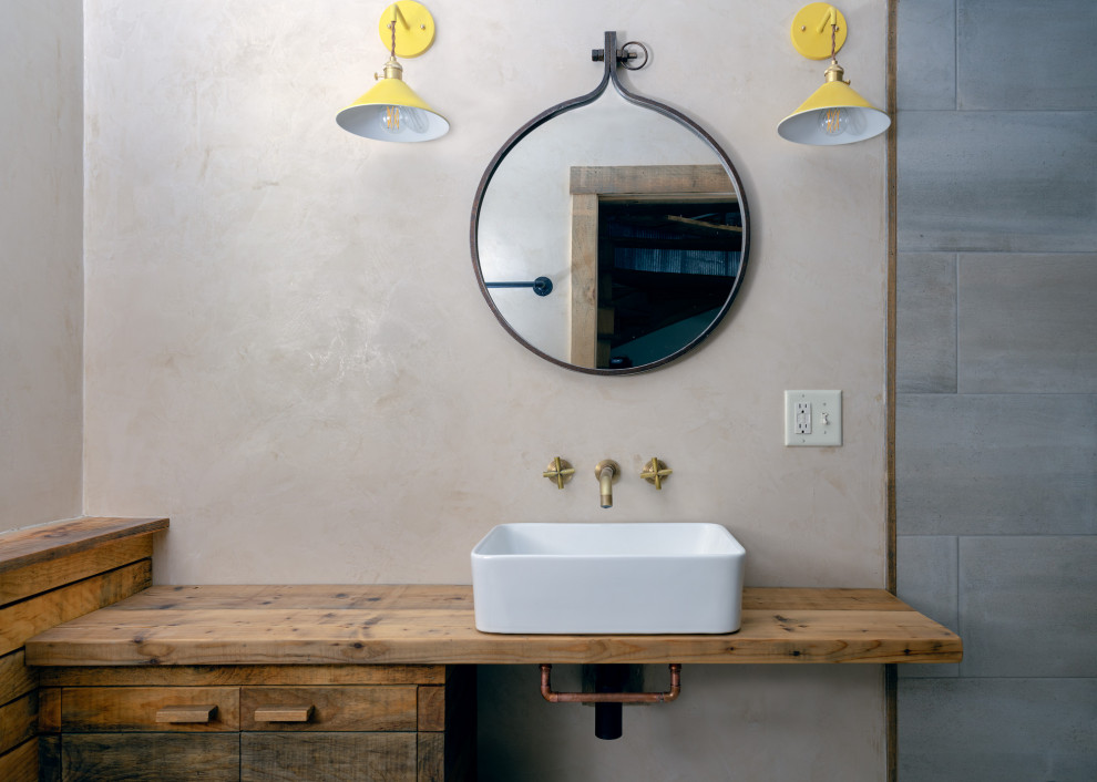Minimalistisk inredning av ett litet badrum med dusch, med skåp i slitet trä, våtrum, en toalettstol med separat cisternkåpa, grå kakel, keramikplattor, beige väggar, klinkergolv i keramik, ett fristående handfat, träbänkskiva, grått golv och med dusch som är öppen