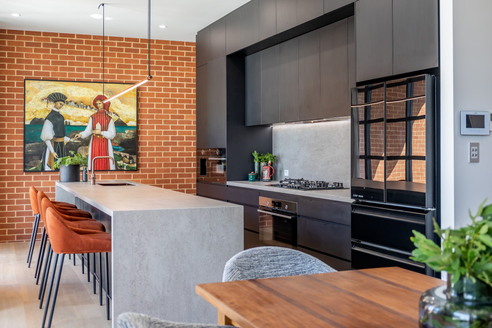 Inspiration for a mid-sized modern galley eat-in kitchen in Adelaide with flat-panel cabinets, black cabinets, grey splashback, light hardwood floors, with island, grey benchtop, an undermount sink, stone slab splashback, black appliances and beige floor.