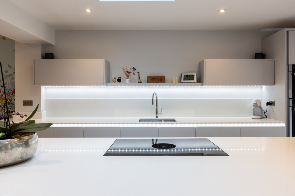 Design ideas for a medium sized contemporary single-wall kitchen/diner in Sussex with flat-panel cabinets, engineered quartz splashback and an island.