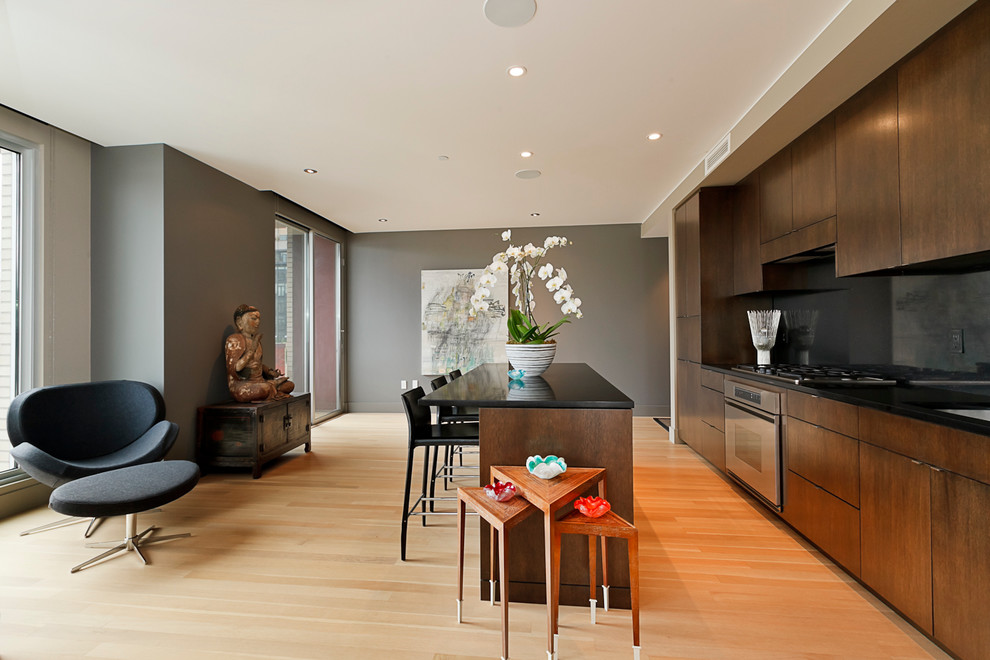Contemporary single-wall kitchen in Portland with flat-panel cabinets, dark wood cabinets, black splashback, stainless steel appliances and glass sheet splashback.